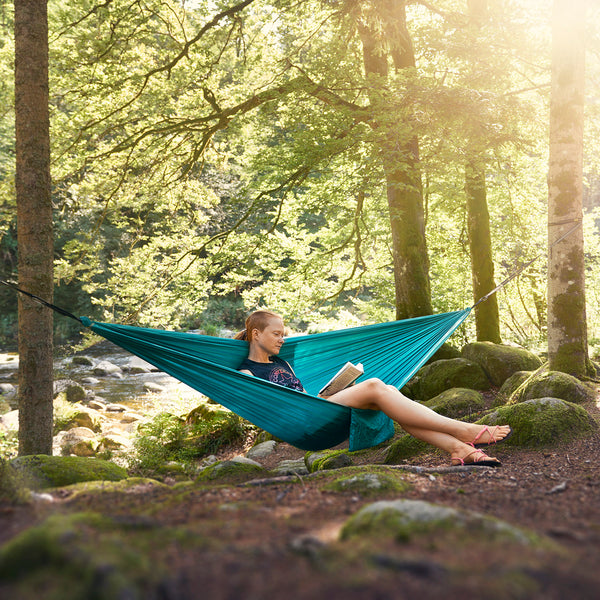 Leichte, hochwertige Outdoorhängematte zwischen zwei Bäumen, türkis